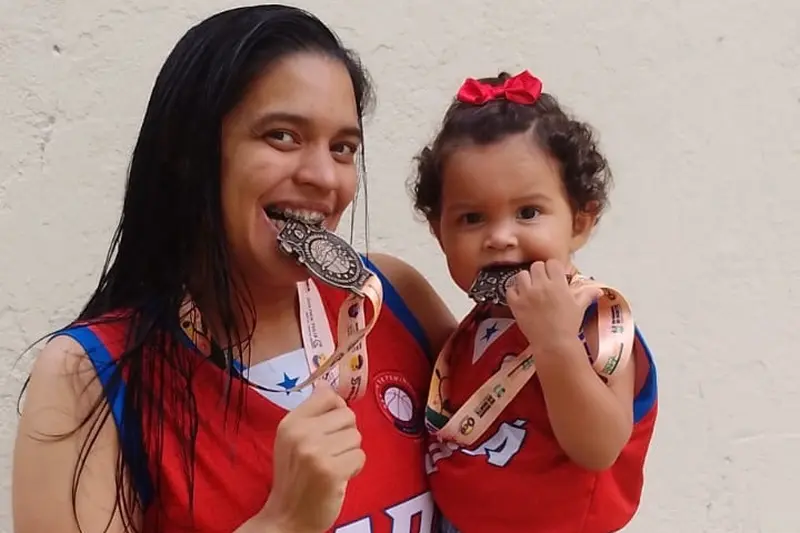 A atleta Silveira Arruda ao lado da filha com a medalha da competição.