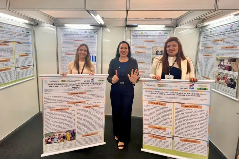 A diretora assistencial, Alnilan Urel, a coordenadora do SCIH, Adrielle Monteiro, e a coordenadora da  Quimioterapia e da UAI, Fábia Araújo, posam com pôsteres de seis dos sete trabalhos apresentados no evento. 