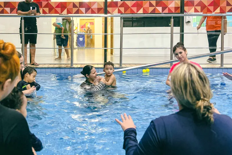 Luiza explica aos familiares como aplicar em casa os estímulos realizados na piscina, promovendo continuidade no processo de reabilitação infantil. 