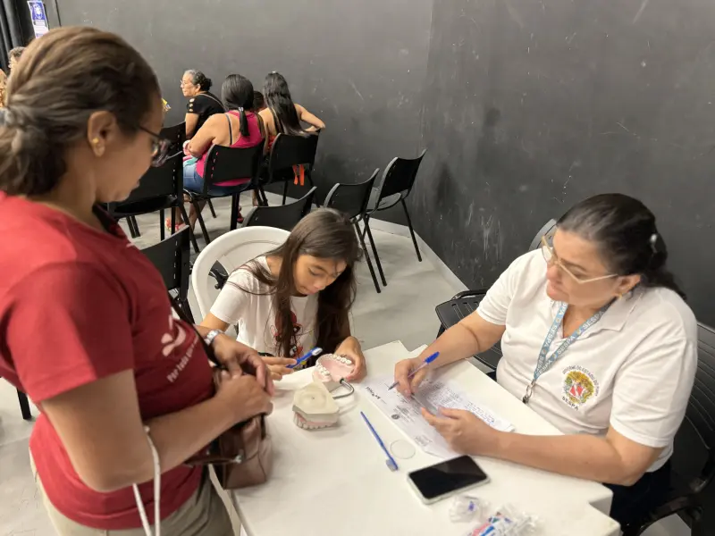 A dona de casa Regina Labareda com a filha, recebendo orientações de saúde bucal 